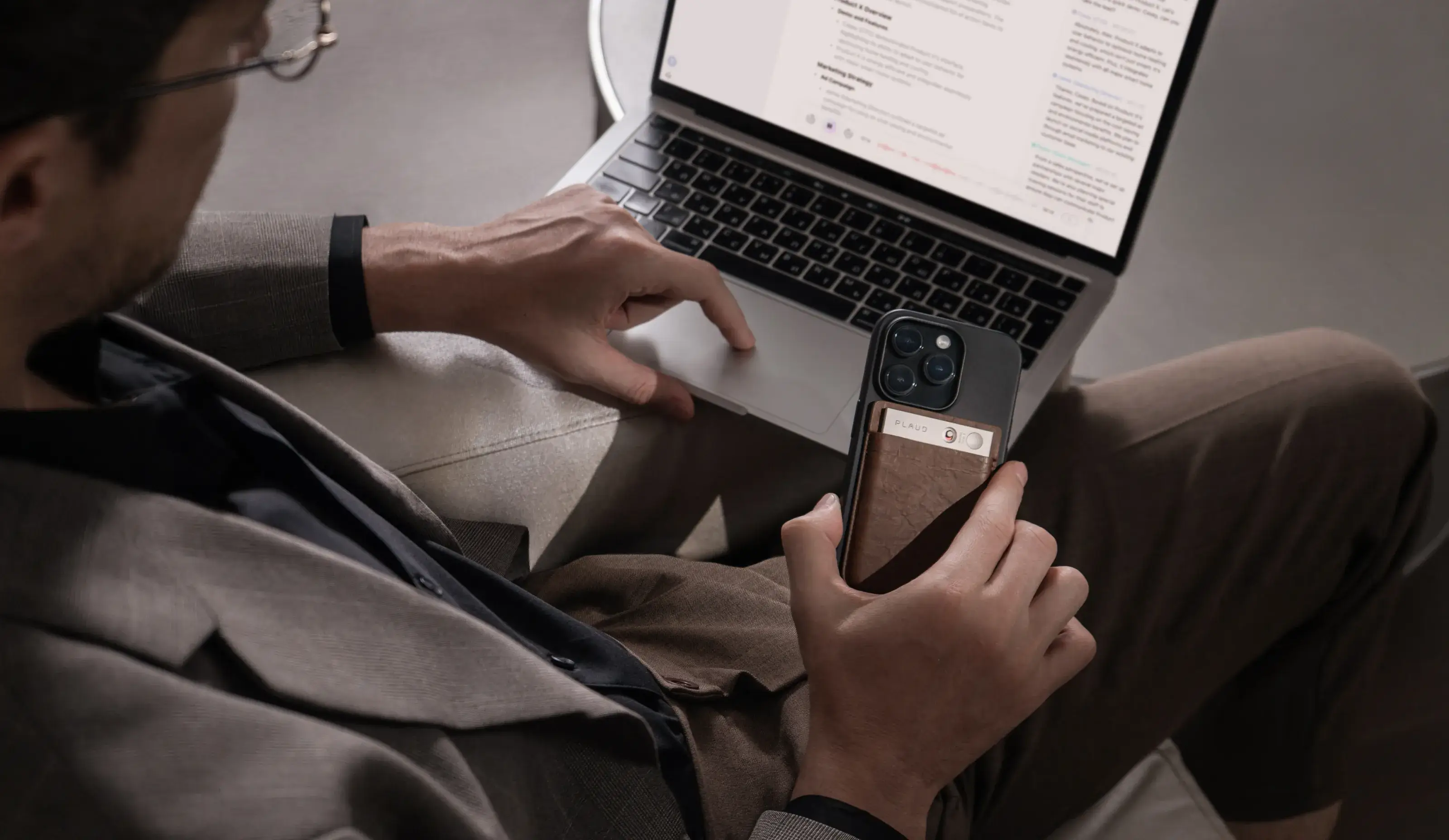 Мужчина работает с готовой расшифровкой на ноутбуке и держит устройство PLAUD
